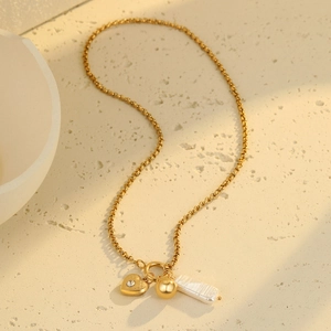 Detail of gold heart pendant necklace with sparkling crystal and baroque pearl on stone