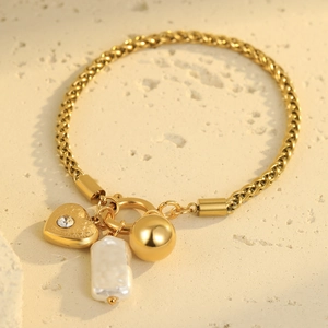 Detail of gold wheat chain bracelet with heart rhinestone, pearl and ball charms