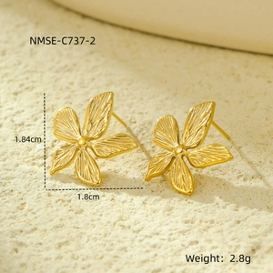 Detailed view of 18k gold flower earrings with brushed texture on a stone background