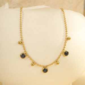Detail of gold beaded anklet with black faceted gemstones and solid mini spheres