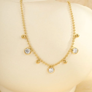 Detailed macro of gold layered anklet with clear crystal pendants and metal beads