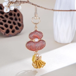 Detailed close-up of a handmade Chinese red gourd charm with pearl and yellow tassels