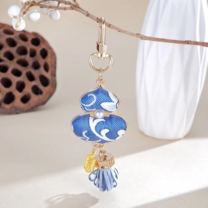 Macro detail of blue porcelain style gourd pendant with pearl inlay and blue tassel