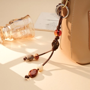 Handmade PU leather cord bag charm with acrylic beads and brown agate stones on a tote bag