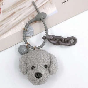 Detail of grey plush teddy dog keychain with heart tag and bell on book background
