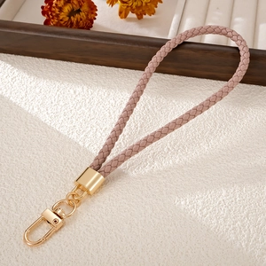 Detail of hand-woven dust pink PU leather phone strap with golden lobster clasp and hardware