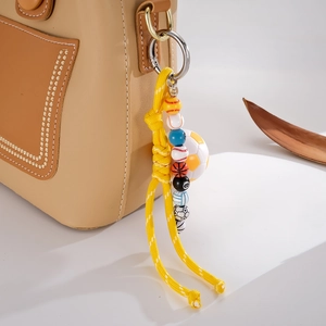 Detail of woven sports ball pendant featuring baseball and soccer beads on leather bag