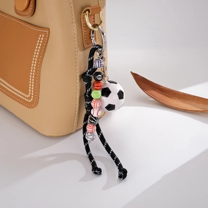 Detail of woven nylon rope bag charm featuring assorted sports ball beads and metal clasp