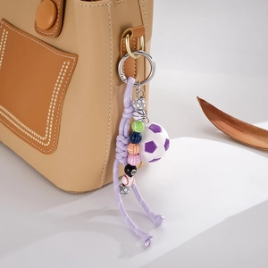 Close-up of sports ball beads and purple nylon rope charm hanging on a leather bag
