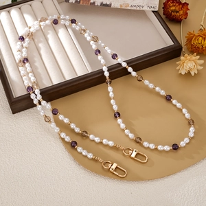 Détail de dragonne de téléphone avec perles blanches et violettes sur plateau