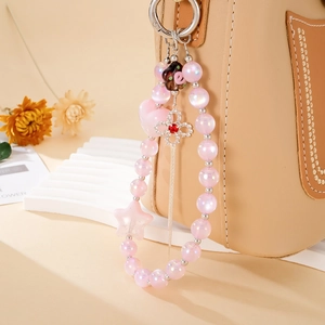 Bijou de téléphone rose avec perles coeur et pendentif trèfle argenté sur sac à main