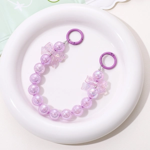 Detailed view of handmade purple beaded charm with colorful bows and circular metal clasps