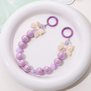 Detail of beaded bag charm featuring iridescent purple pearls and cream bow beads