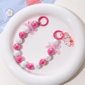Macro detail of mermaid bead chain with acrylic rabbit pendant and pink bow charm decoration