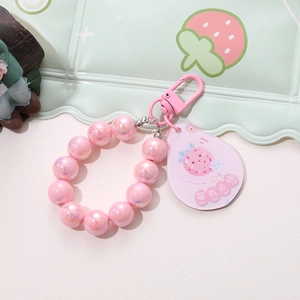 Detail of pink pearlescent beaded strap and strawberry acrylic charm keychain