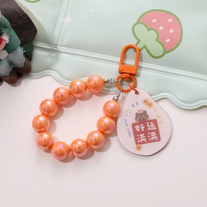 Detail of beaded keychain with orange pearls and acrylic lucky bear pendant charm