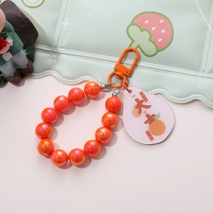 Close-up of orange beaded keychain with acrylic tag and lucky orange illustration