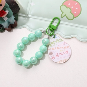 Close-up of light green mermaid beaded keychain with acrylic tag on a strawberry tray