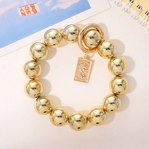Détail d'un bracelet en perles dorées avec un pendentif pièce vintage de portrait de reine