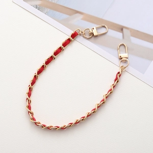 Close-up of golden metal chain interwoven with red leather and lobster clasps