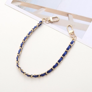 Detail view of woven gold metal chain with navy blue leather strap and lobster clasps