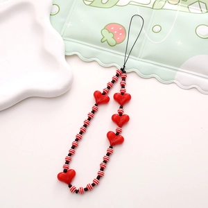 Close-up of handmade striped beads and red heart charms on a short phone wrist strap