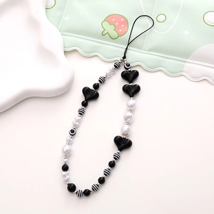 Detailed macro shot of black heart beads and striped pearls on a beaded phone wrist strap