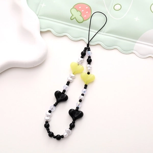 Detail of handmade beaded phone strap with colorful heart charms and striped beads on a tray