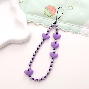 Close-up of purple heart and striped resin beads on a handmade phone wrist strap