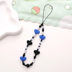 Detail of blue and black heart beads with white pearls on a striped phone wrist strap