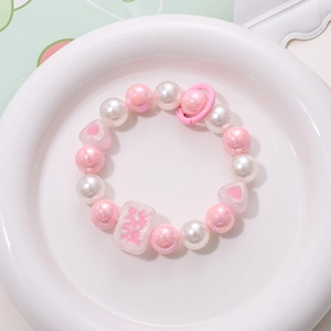 Close-up of beaded phone strap with pink Mahjong charm and iridescent heart beads