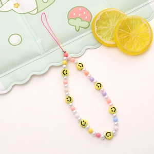 Macro detail of colorful beaded phone strap with yellow smiley face and macaron beads