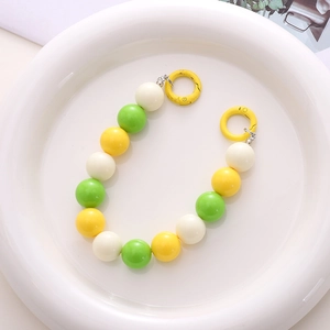 Detailed view of 16mm acrylic round beads in green and yellow with yellow spring ring clasps