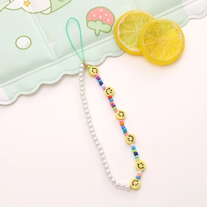 Detailed macro view of colorful smiley face beads and white pearls on a mobile wrist strap