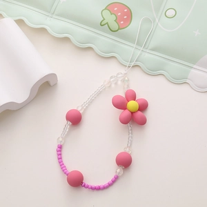 Detail of beaded phone strap with pink matte beads and flower pendant on soft background