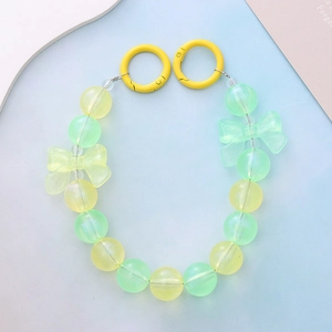 Detail of beaded phone strap with green and yellow frosted beads and bow accents