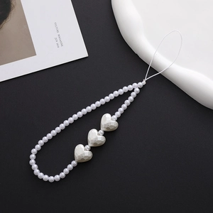 Close-up of white beaded phone strap with geometric heart charms on a black background