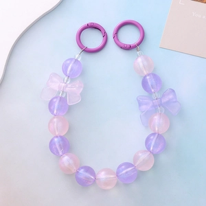 Close-up of mermaid pearl phone chain with purple bows and luminous beads on blue background