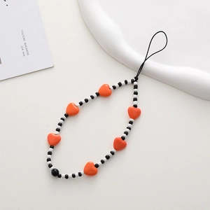 Detail of vibrant orange heart beads and monochrome round beads on a phone wrist strap