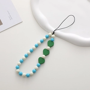 Detail of beaded phone strap with blue beads and green wooden hearts on a white tray