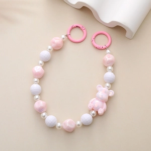 Pink UV bear charm with beaded phone strap and spring ring clasp on beige background