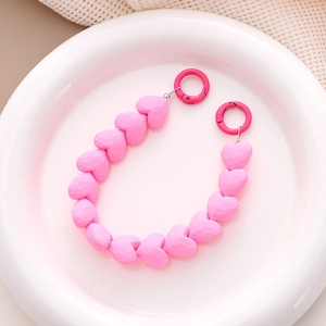 Macro detail of faceted pink heart beads and round spring buckles on phone strap