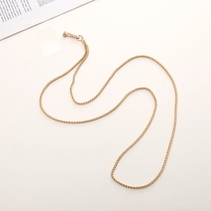 Close-up of golden woven metal chain strap with high-gloss swivel lobster clasps