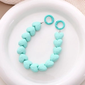 Detail of mint green heart-shaped faceted beads on a mobile chain with spring rings