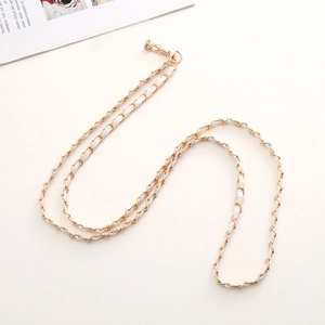 Detail of gold metal chain woven with white leather featuring a secure spring lobster clasp