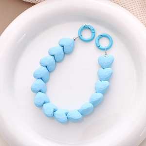 Close-up of sky blue faceted heart beads with spring ring clasps on ceramic plate