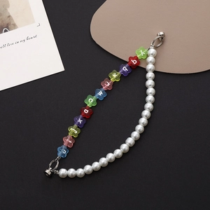 Detail of beaded phone strap with white pearls and colorful flower charms and silver clasp