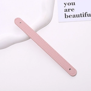 Detailed view of a pink lychee grain leather phone strap with white stitching and mounting holes