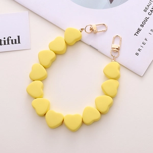Dettaglio del cordino con perle a cuore giallo limone opaco e moschettoni dorati per borsa