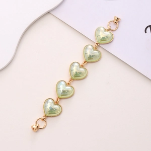 Detail of golden bracelet with five light green pearlescent heart charms and magnetic clasp